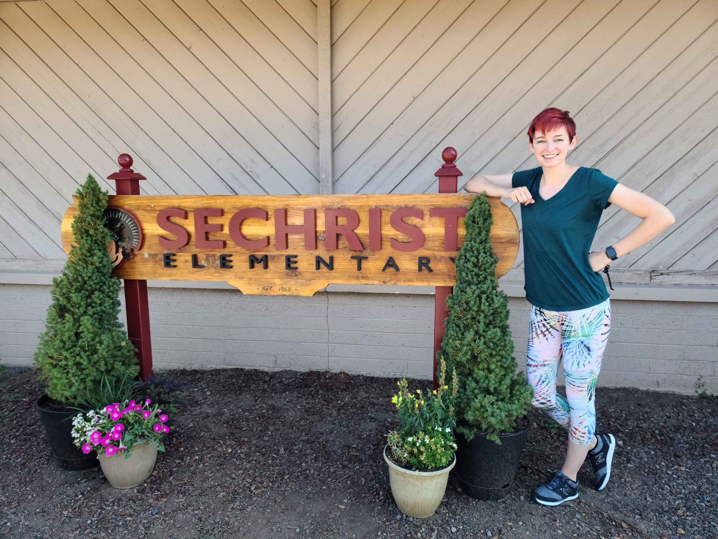 Madison Fisher, physical education teacher, posing with the Sechrist Elementary sign.