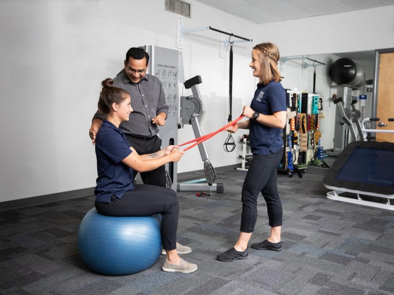 A physical therapist at N A U Flagstaff campus works with students on Bosu ball and exercise strap.