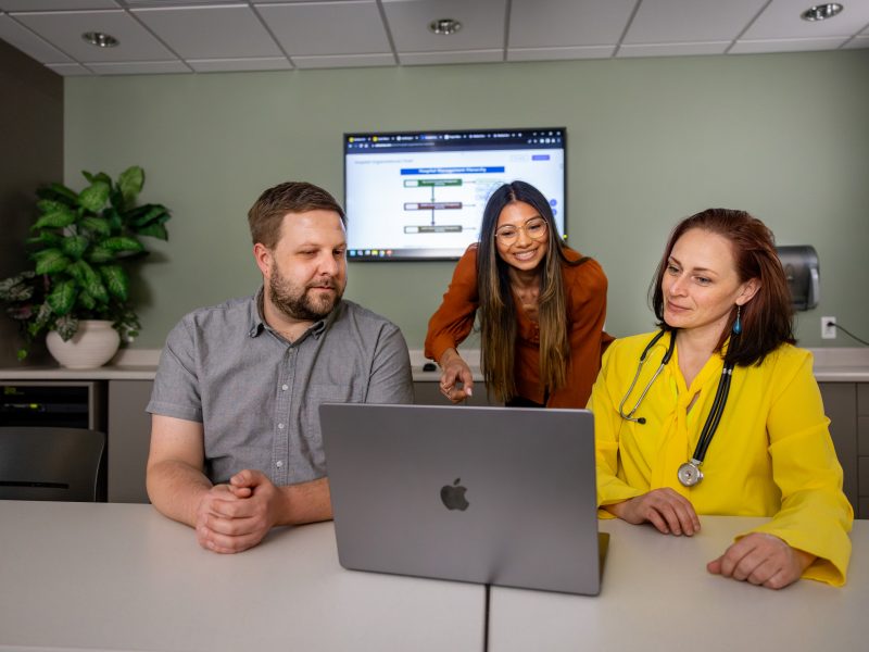 Three health admins looking at a laptop.