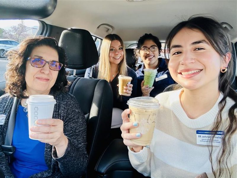 NAU Communication Sciences and Disorders students and professor Fe Murray holding coffee and smiling inside a vehicle.