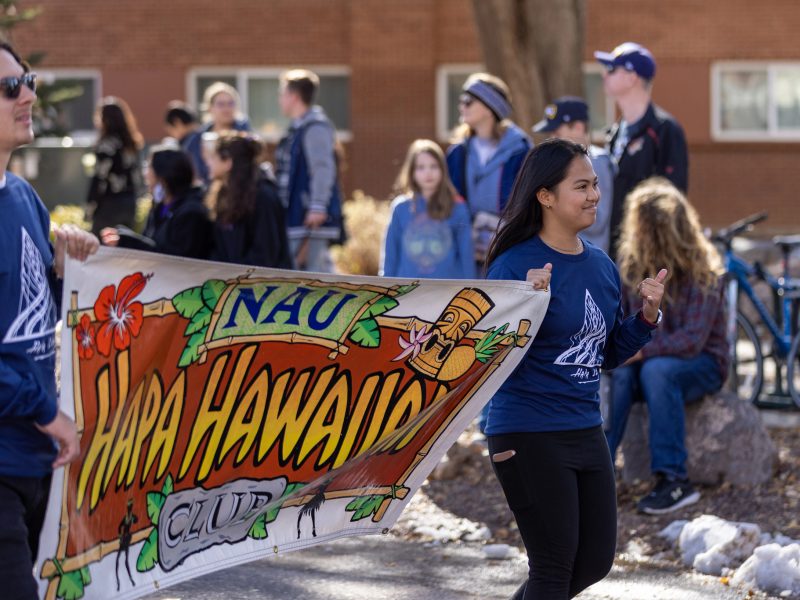 N A U students marking in parade with a banner that says Hapa Hawaiian Club.