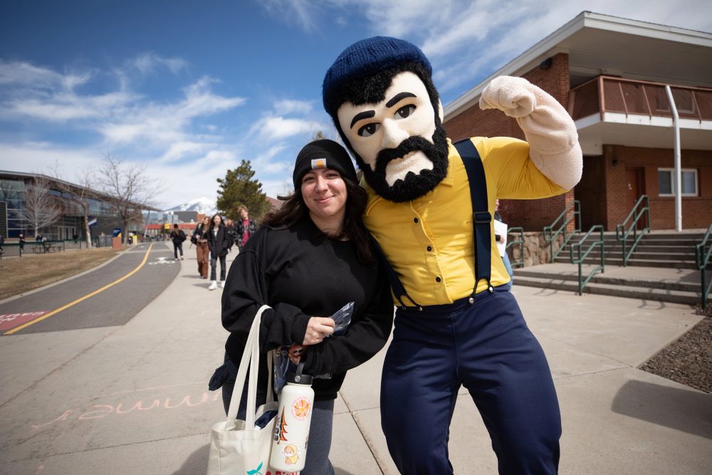 N A U Lumberjack posing for a photo with student.