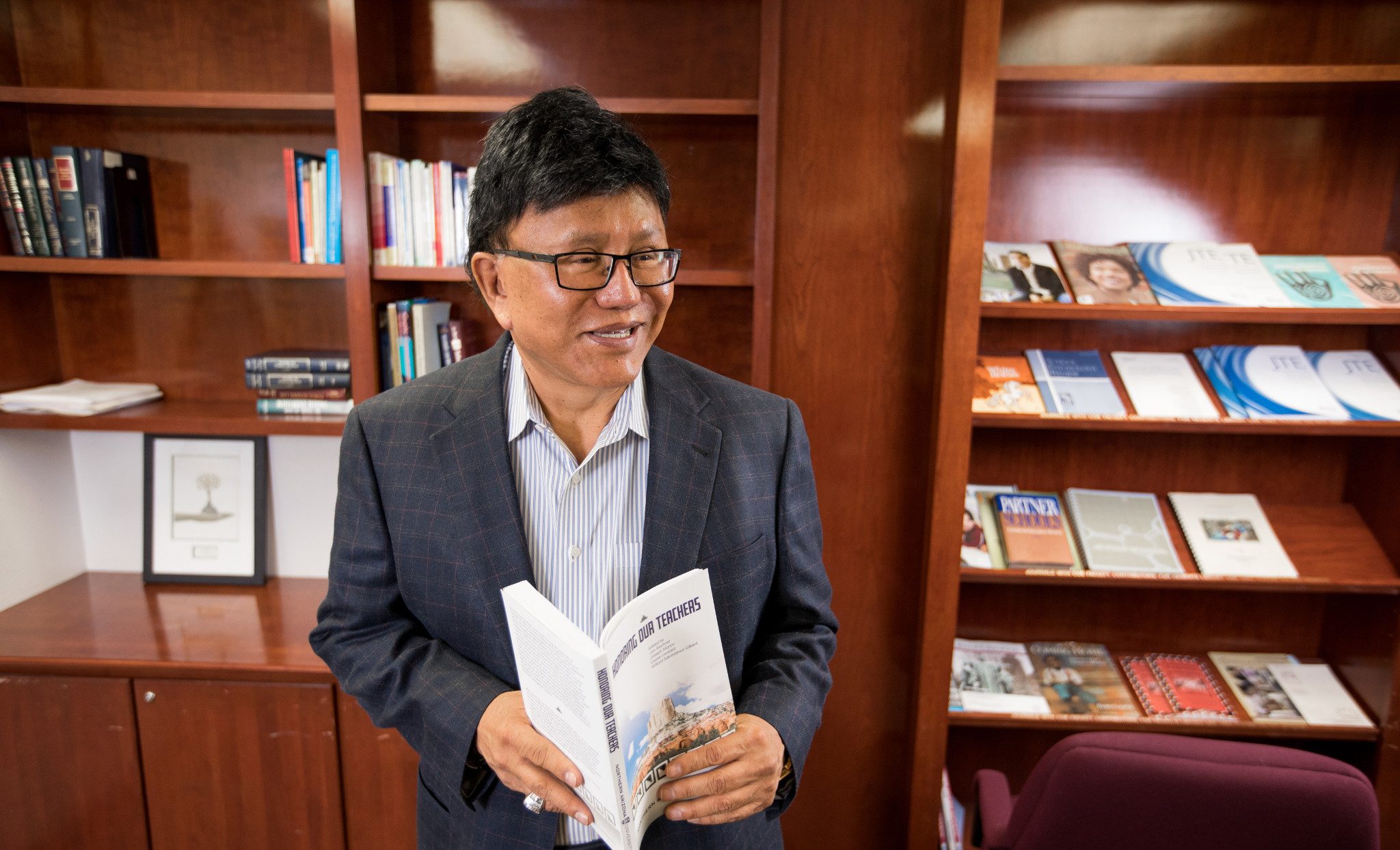 Professor Joseph Martin standing in a room, holding a book.