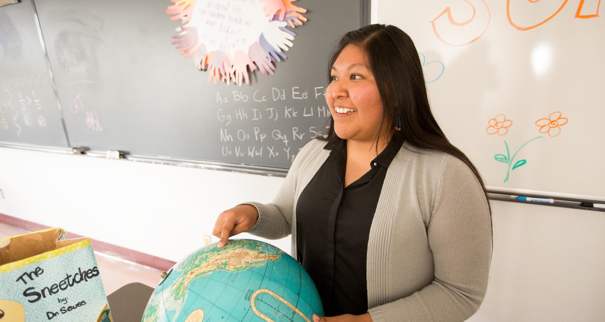 Student teacher points to globe in class.