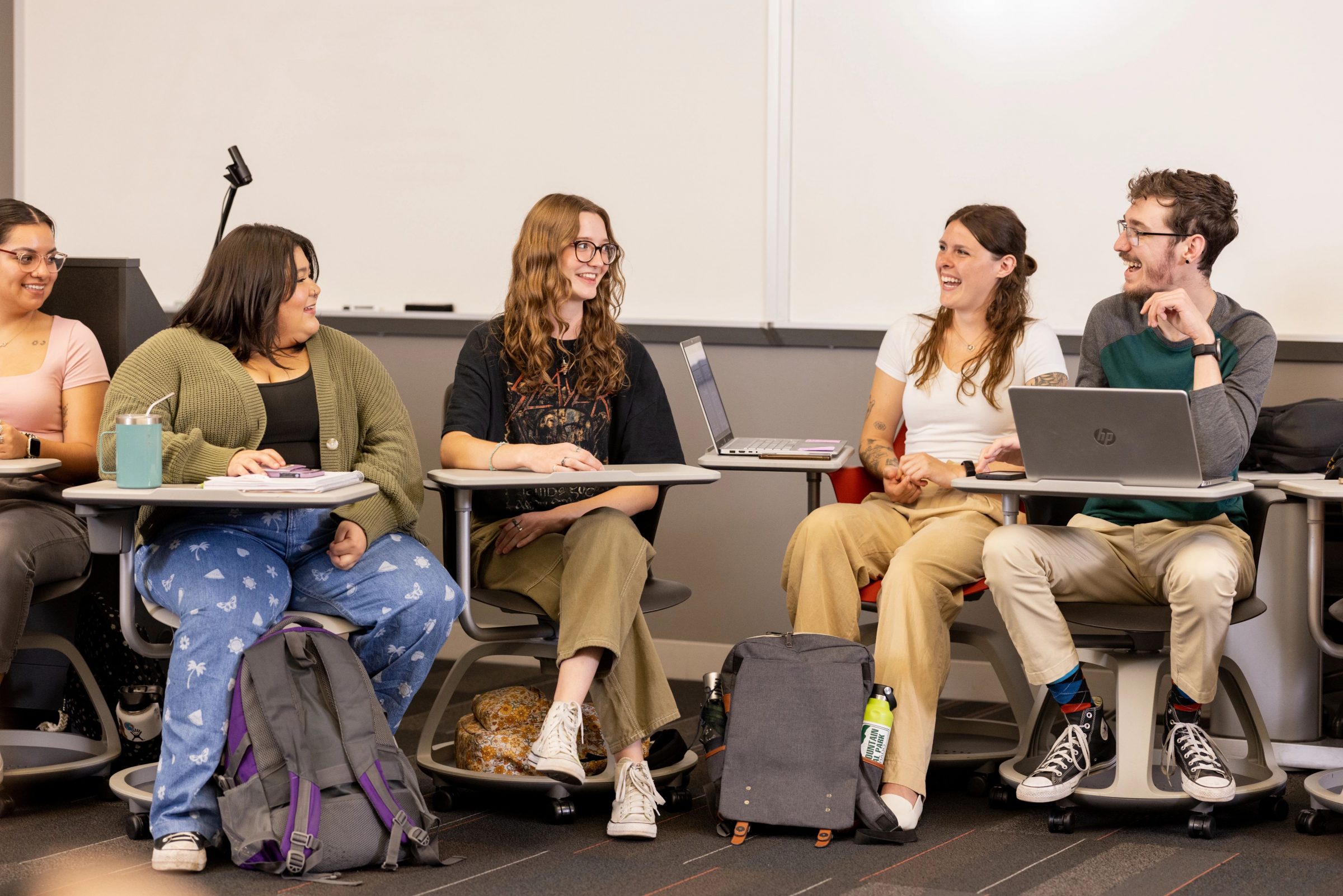 Students smile as they sit in a group in a psychology classroom.