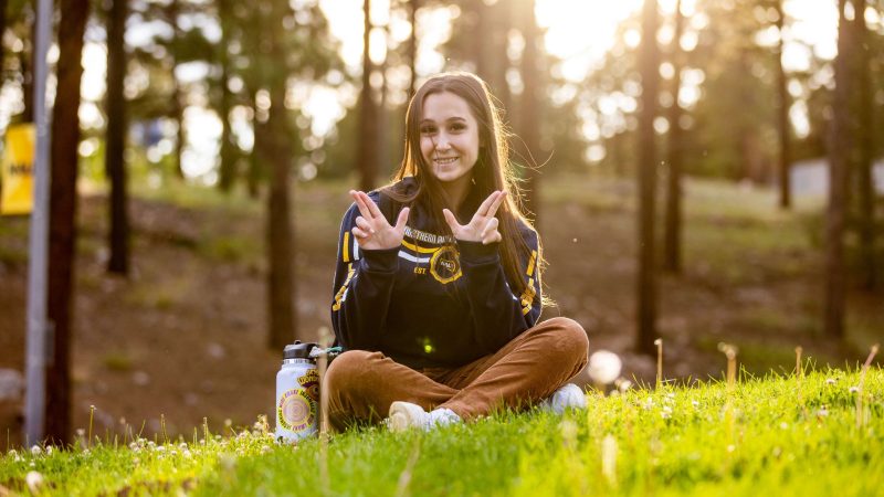 A student smiles and poses outside at Northern Arizona University.