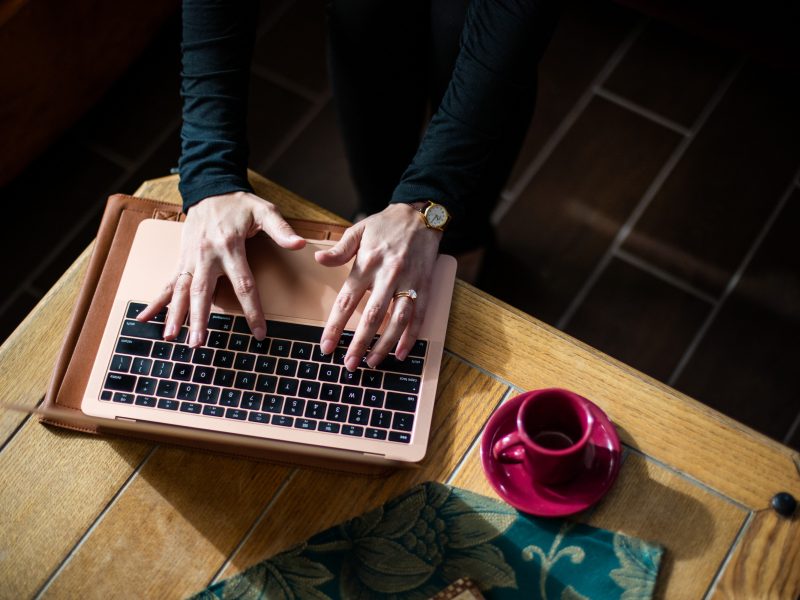 A student working on their laptop from home with a coffee cup on the table.