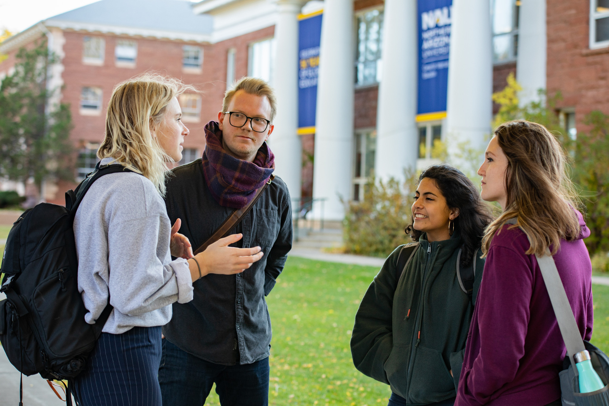 Four people talking in front of a campus building.