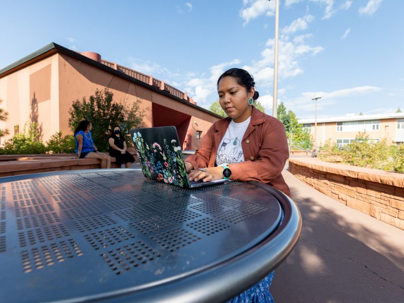 A student works on a laptop outside of the N A U Native American Cultural Center.