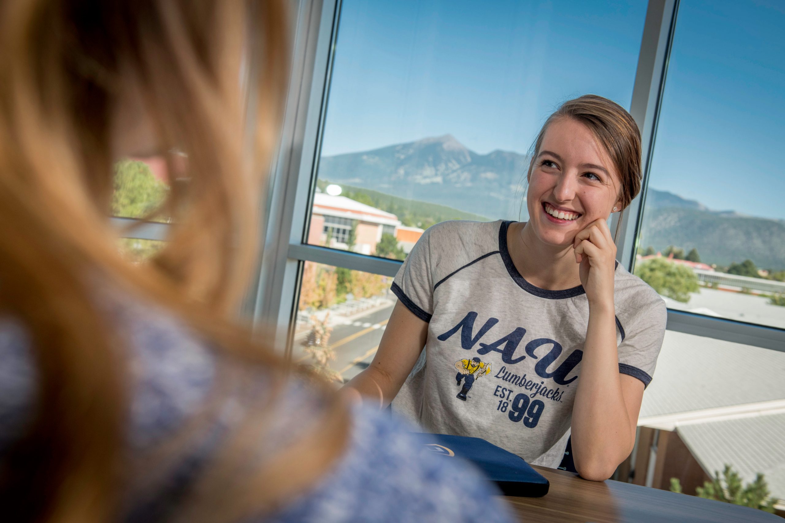 Student smiling while wearing vintage styled NAU shirt.