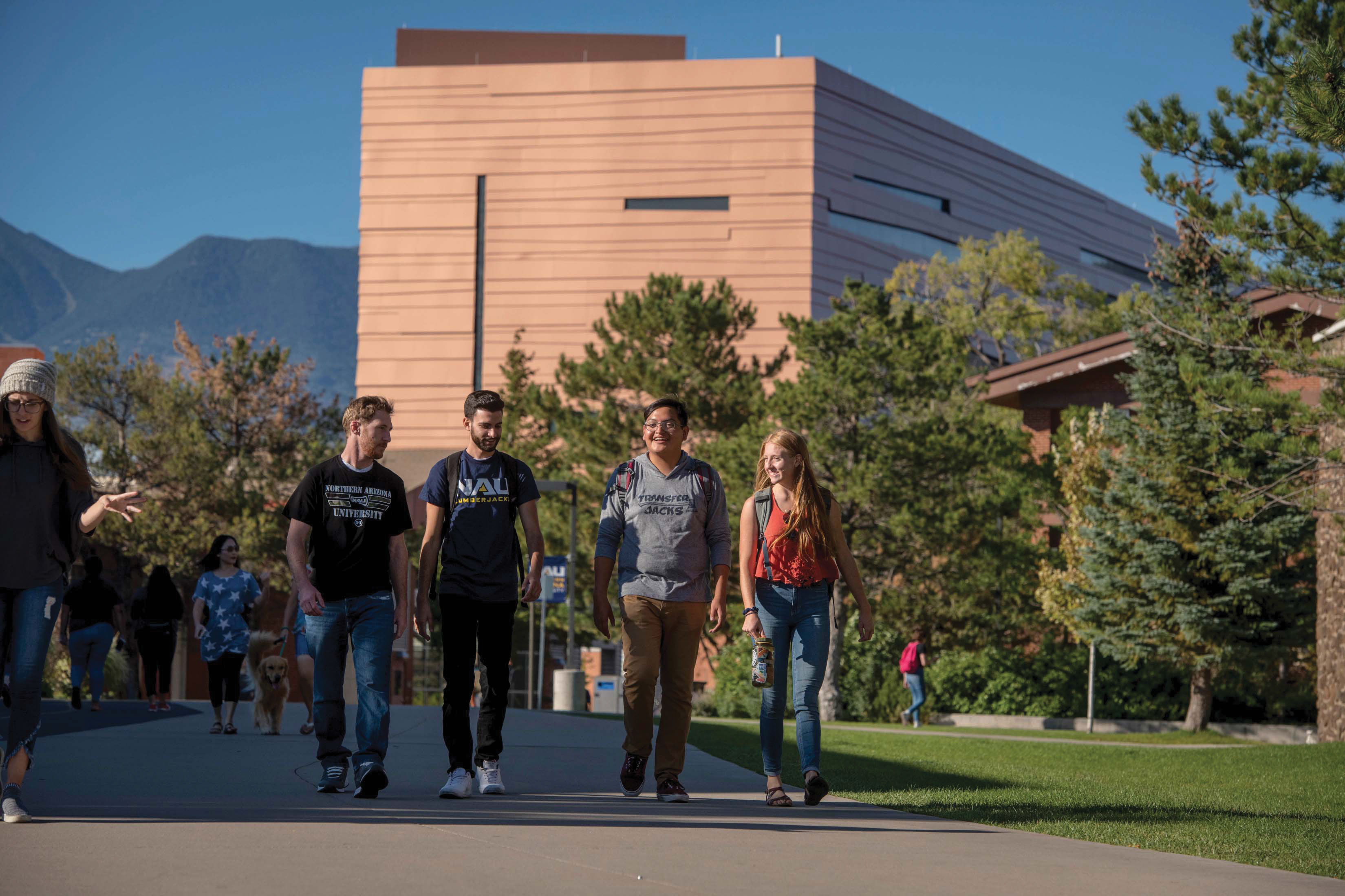 Four students smiling while walking together outside.