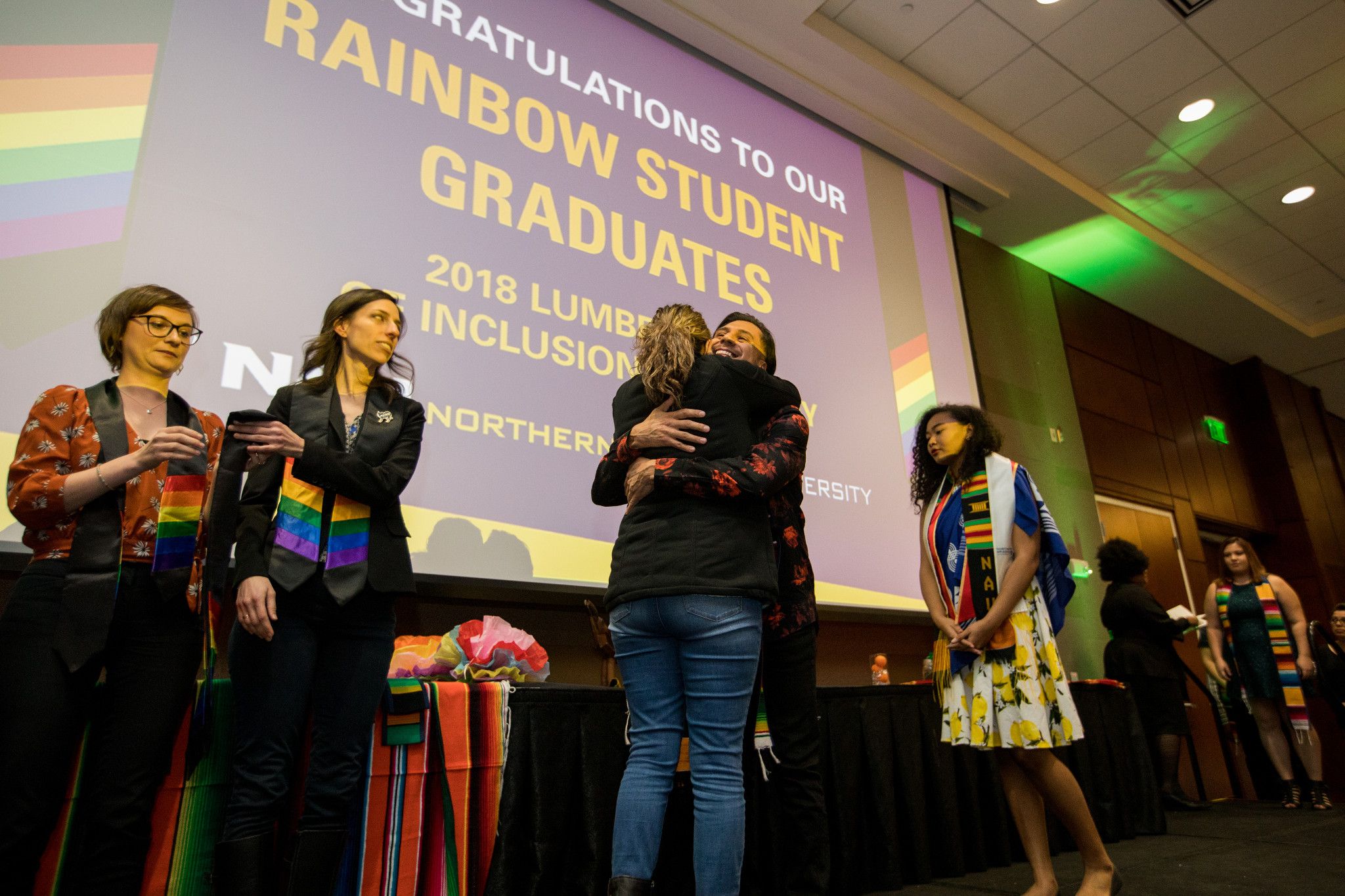 Rainbow convocation with students hugging.