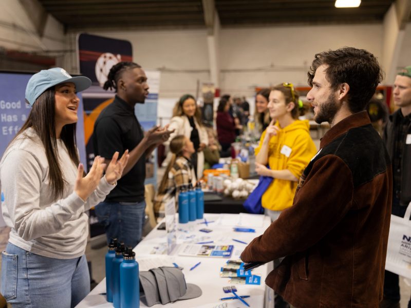 N A U students speaking to visitors at a career fair.