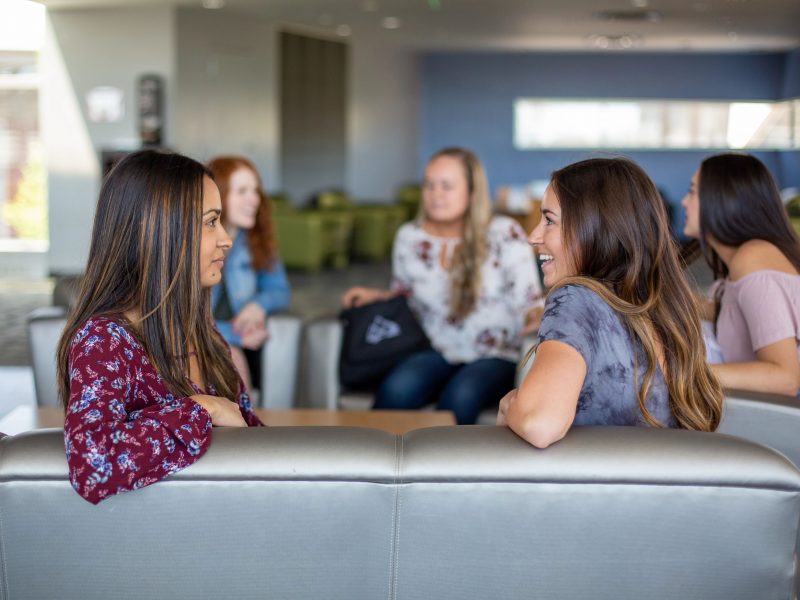 Sorority students are sitting and talking with each other.