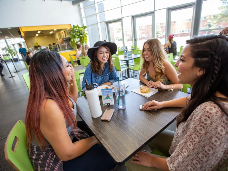 Four students sitting at a table and talking in the Union.