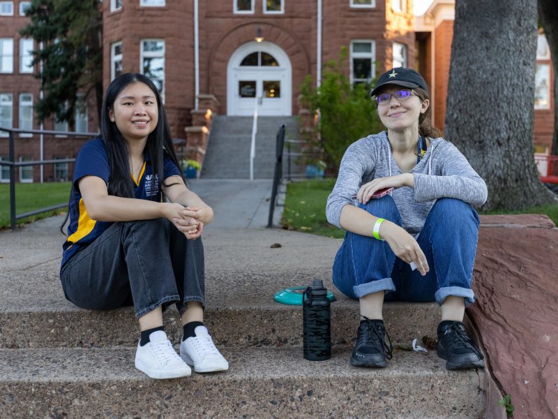 Two students sitting outside on campus.