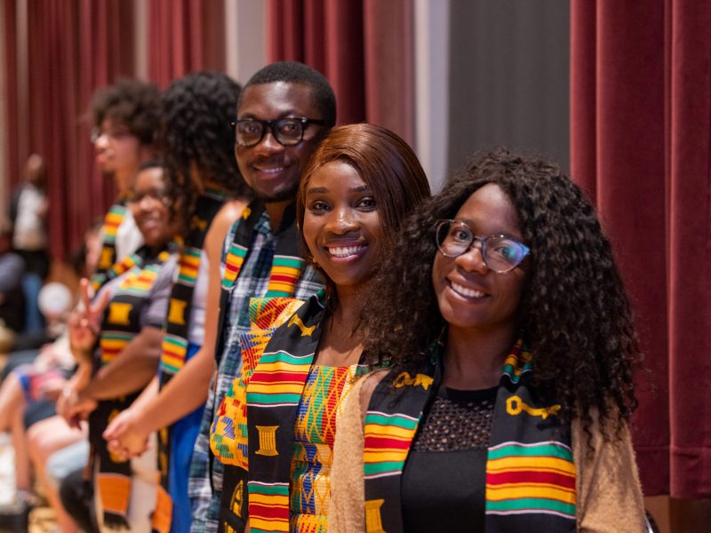 Students wearing colorful Black Convocation Awards stoles smile at the camera.