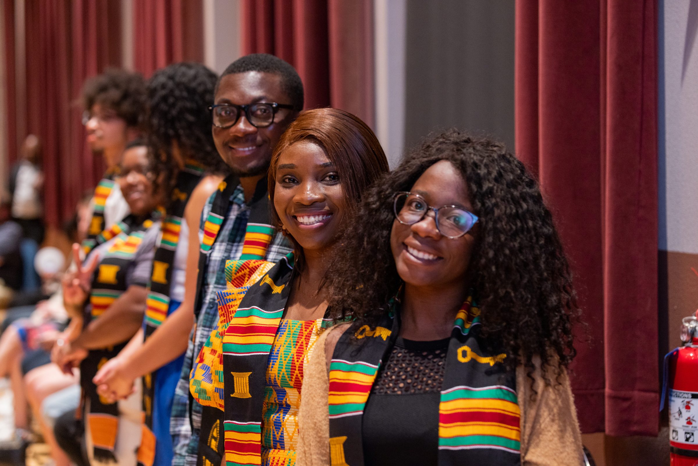 Students wearing colorful Black Convocation Awards stoles smile at the camera.
