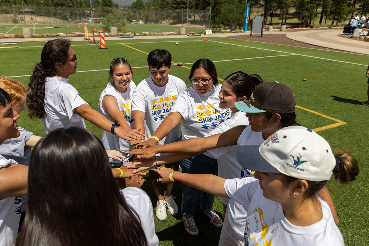 Indigenous students wearing SKO Jacks shirts gather on the soccer field.