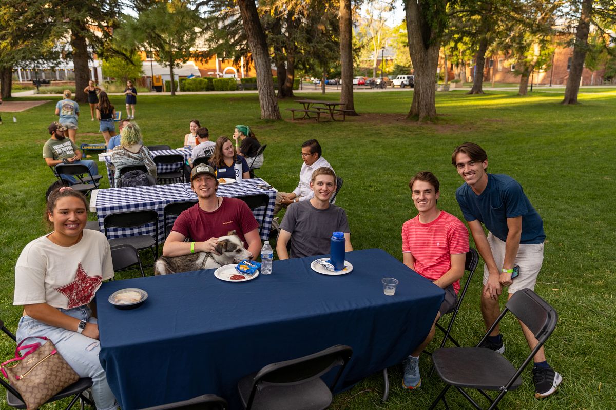 Transfer students sit at picnic tables on the main lawn and eat.