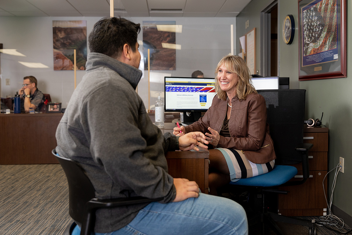 A student meets with a smiling advisor in the Veteran Success Center.