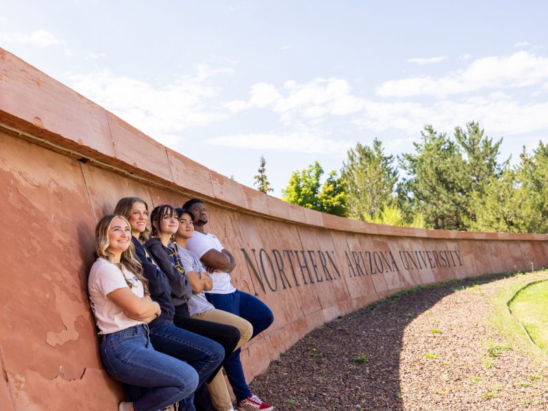 N A U student standing in from of Northern Arizona University sign.