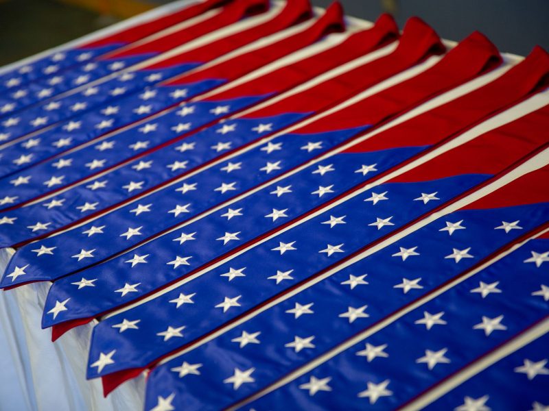 A group of stoles (red with white stars on blue background) line a table.