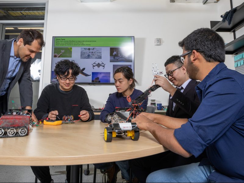 Student researchers inspecting robot