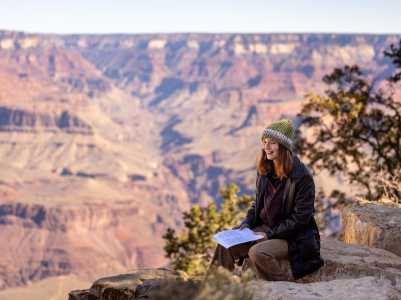 A photo of a women sitting at the Grand Canyon.