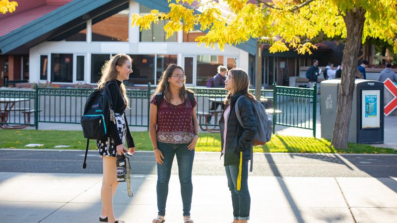 Three students engage in conversation at the university union.