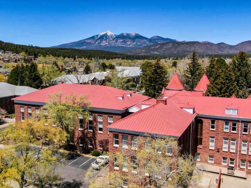 A drone photo of NAU Flagstaff campus with mountains in the background.