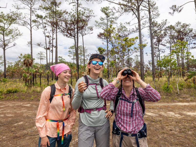 Students outdoors in Belize looking through binoculars.