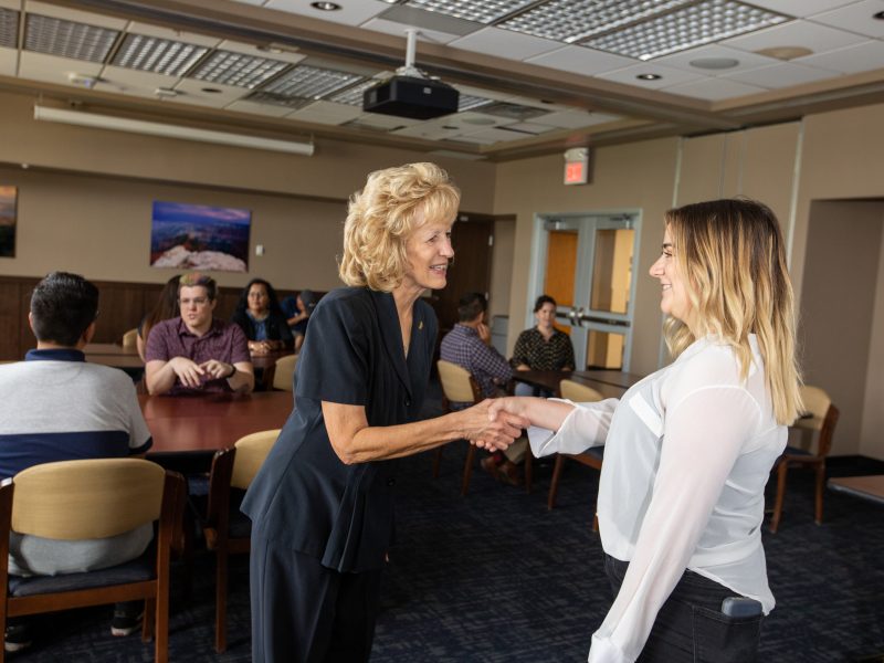 An NAU alum shaking hands with a current student.