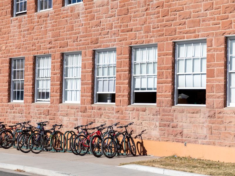 A line of bicycles against a brick wall.