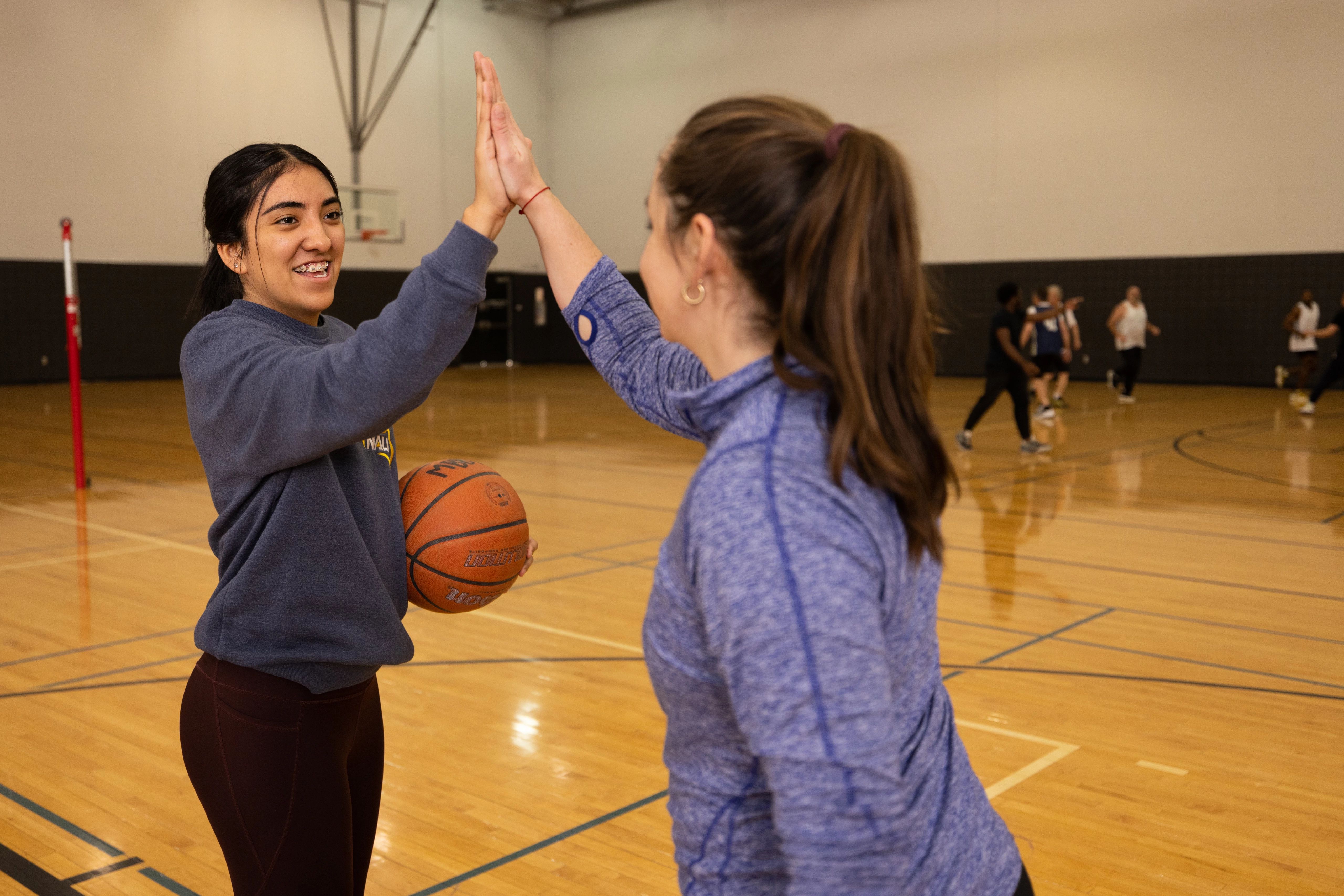 Two students high-fiving at the basketball court.