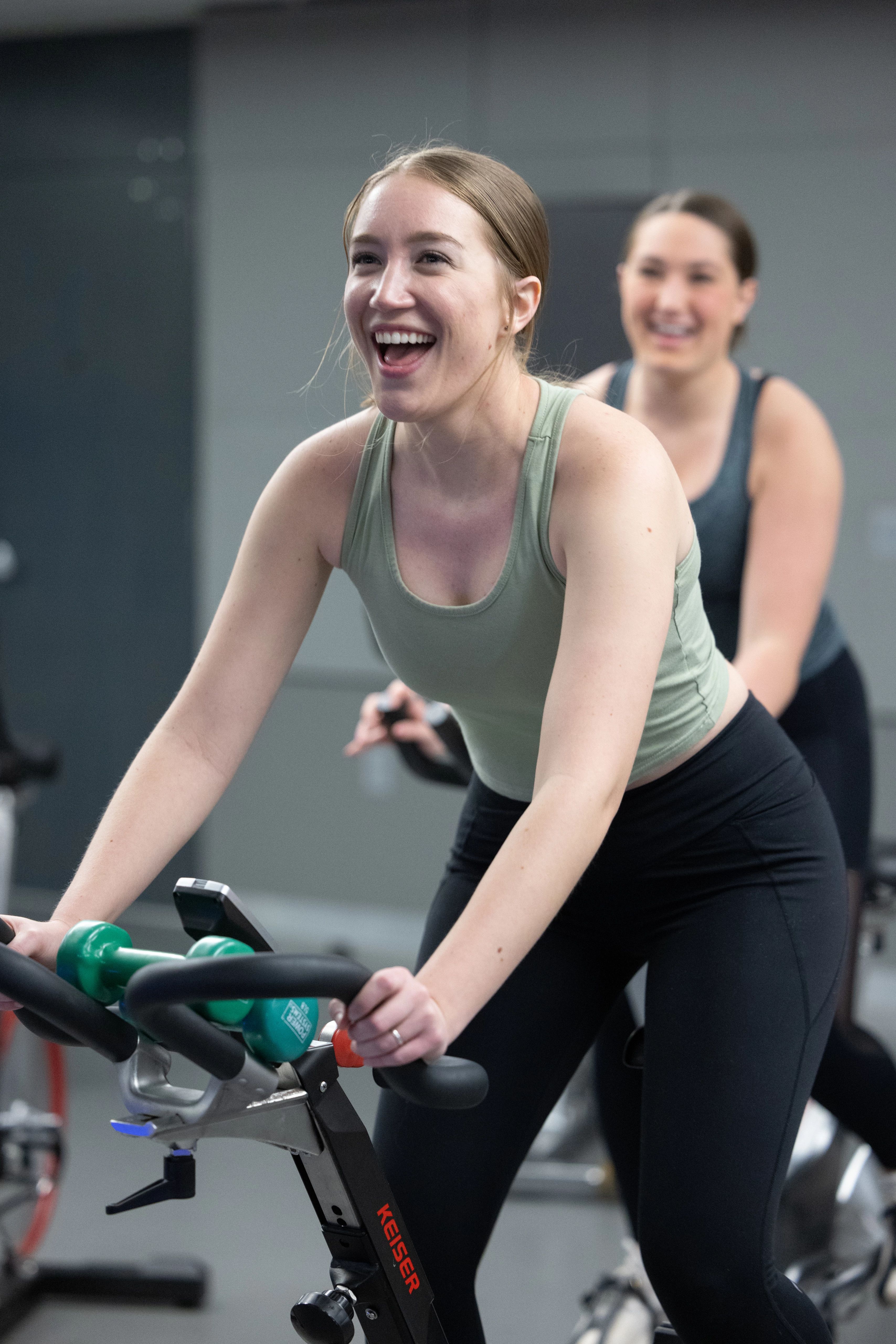 Female student smiling on a bike machine.