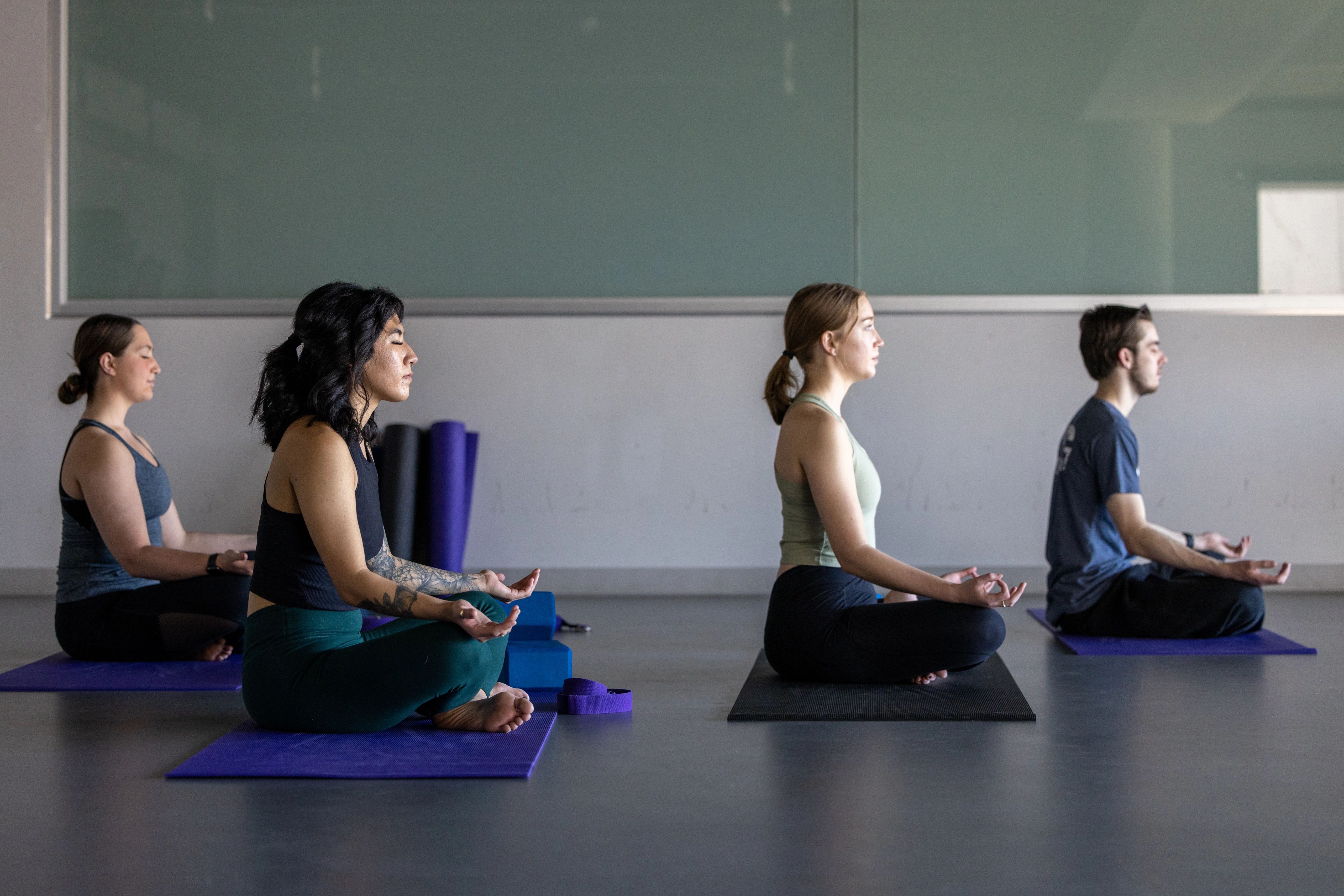 Four student sitting in an upright yoga pose facing the right.