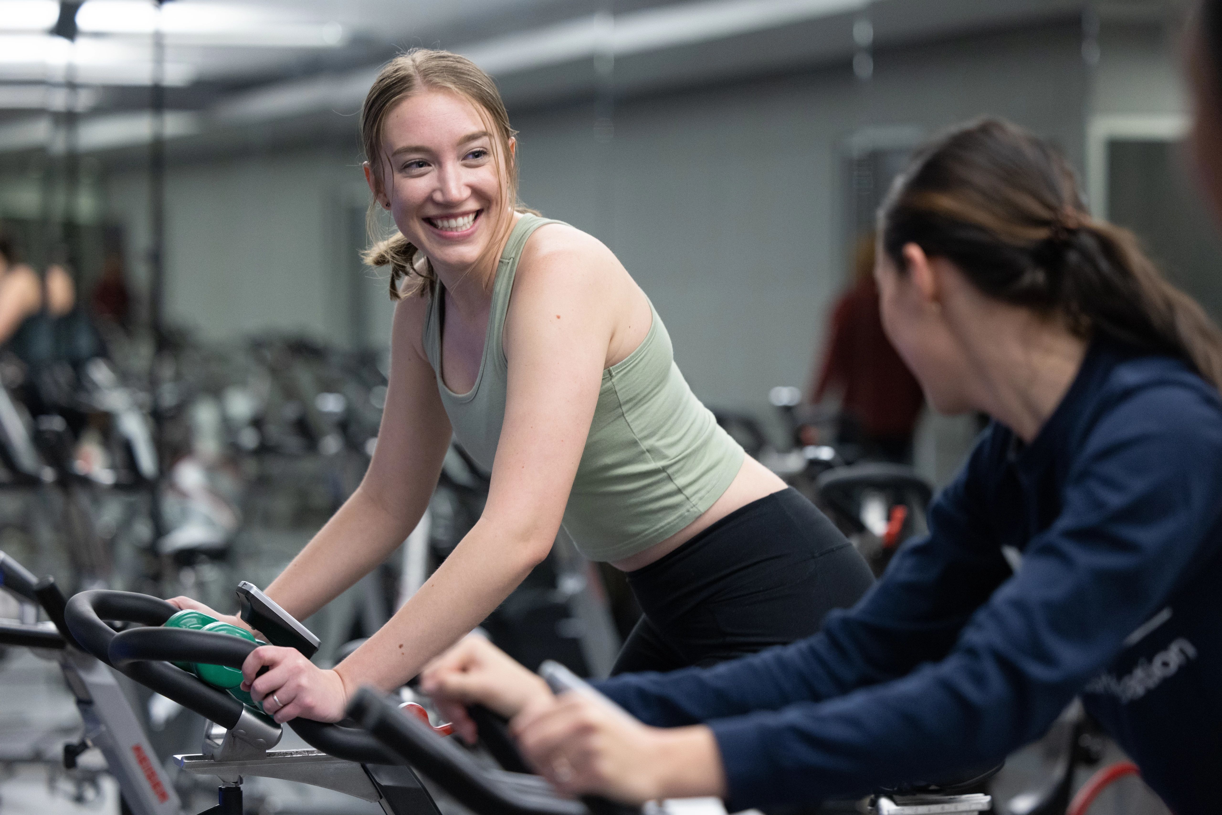 Student smiling while using exercise bike at N A U.