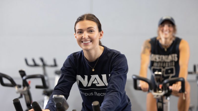 Female student smiling while using exercise bike.