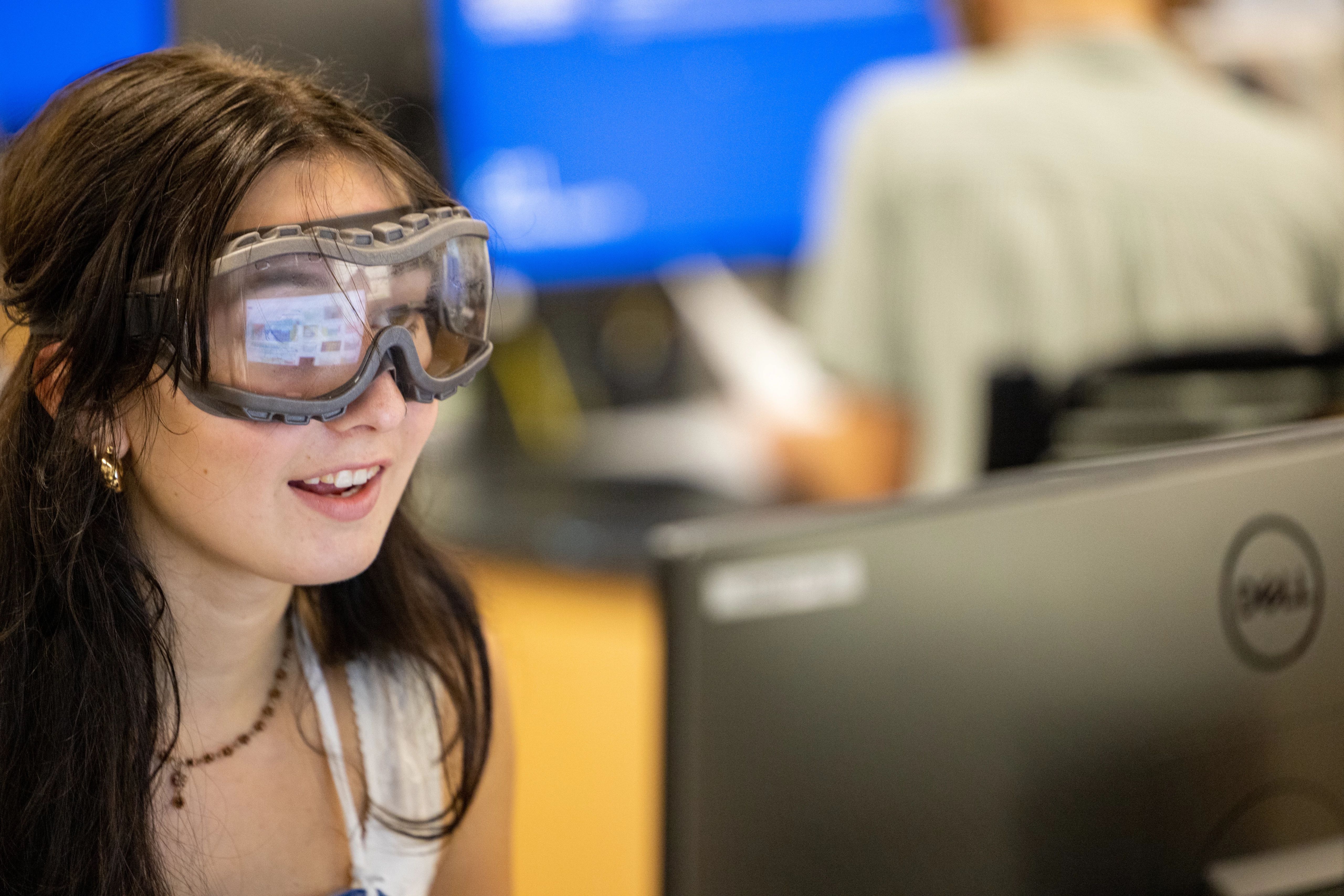 A student wearing goggles working on a computer at N A U