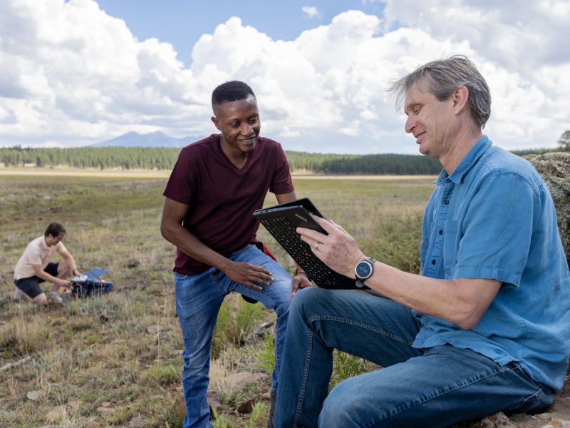 Faculty member and student in a field looking at an ipad