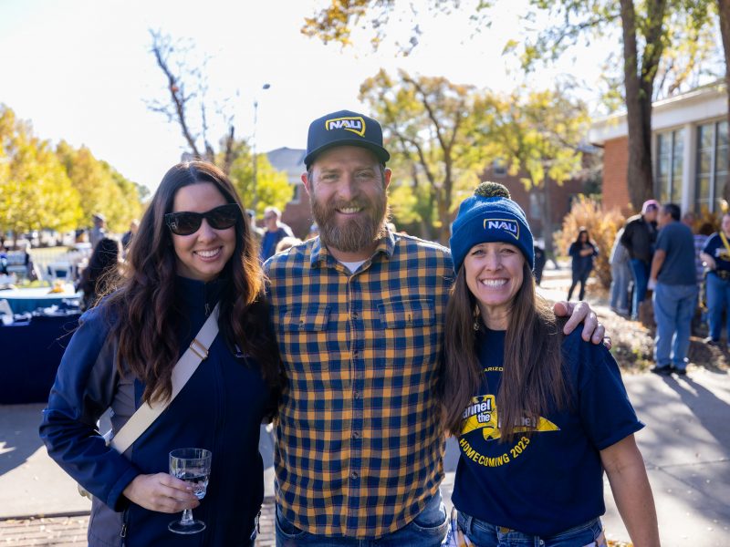 Northern Arizona University alumni outdoors smiling at camera.