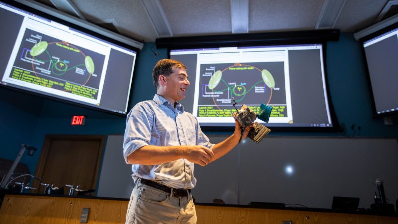 Josh Emery uses a satellite model to demonstrate how they orbit in space.