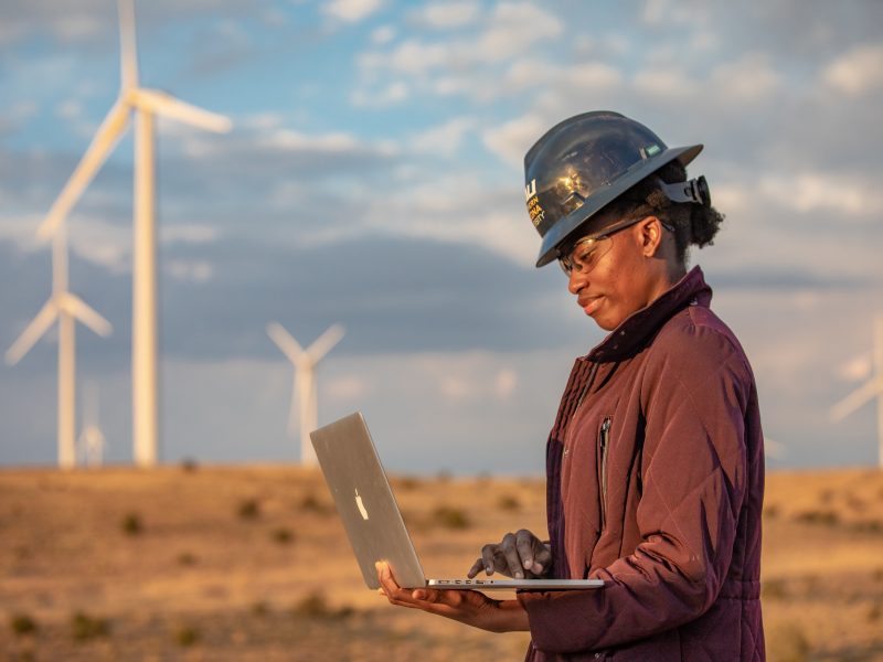 Student writing a report on a computer at a wind farm.