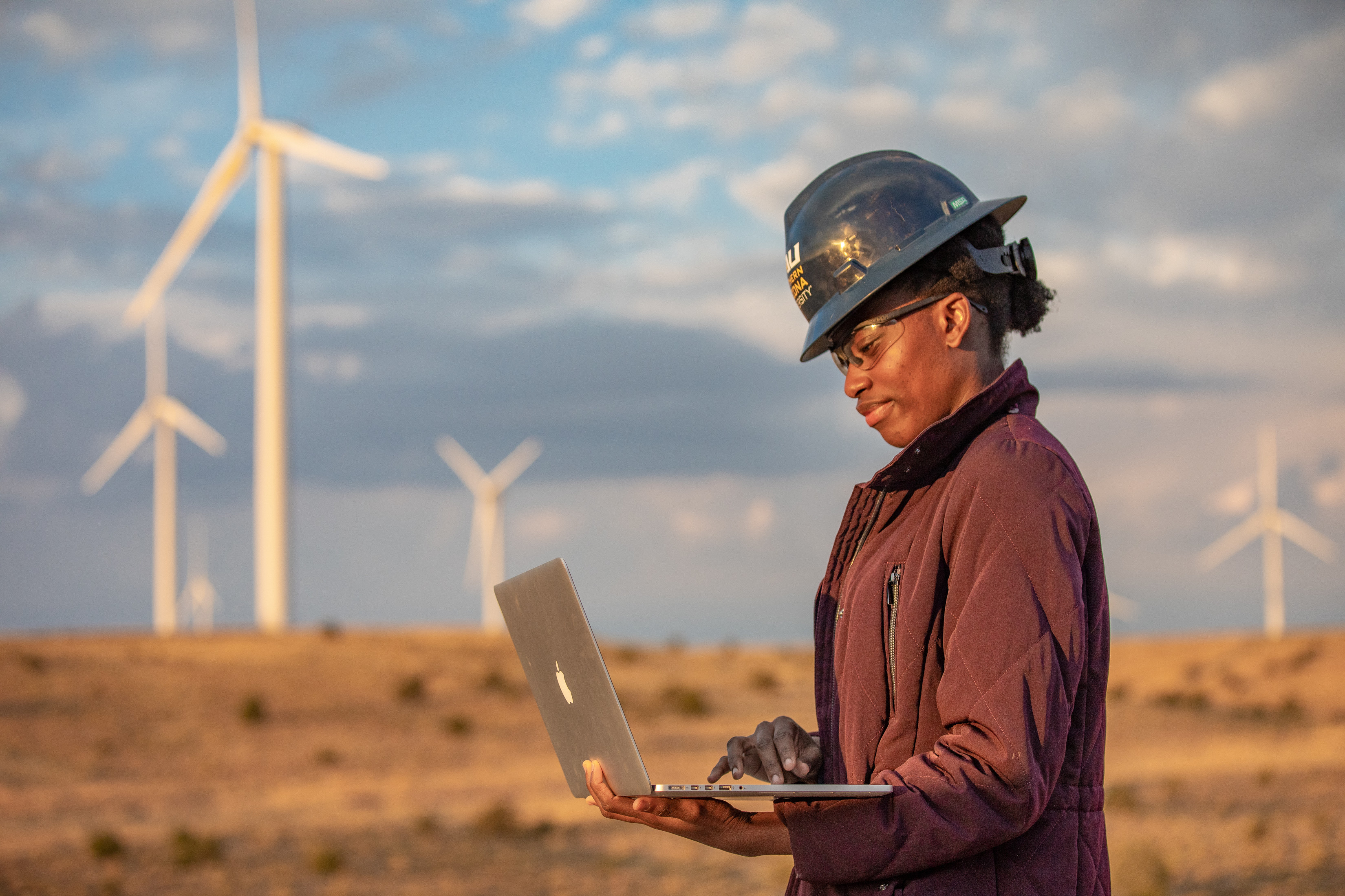 Student writing a report on a computer at a wind farm.