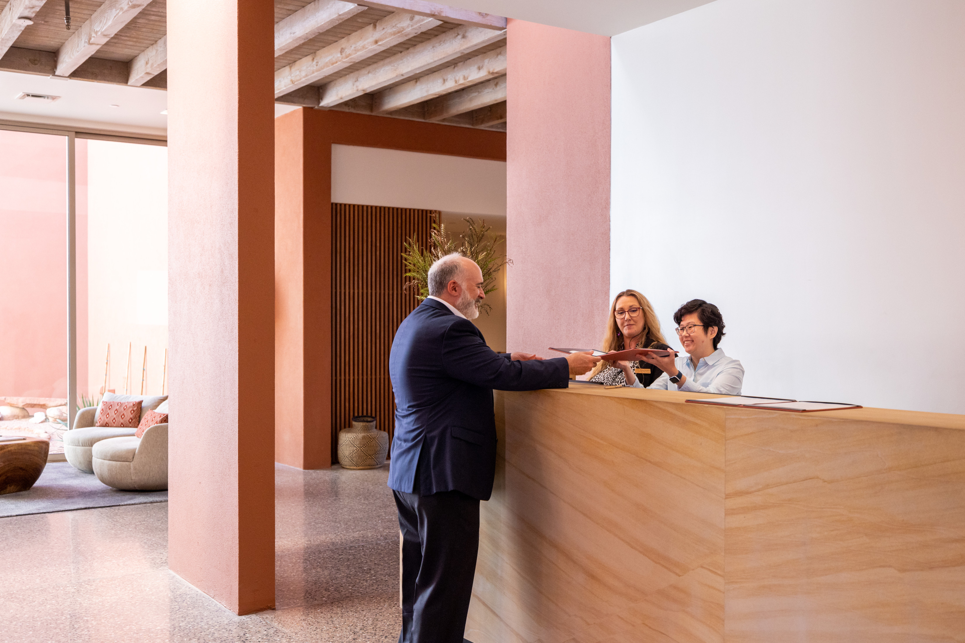 People standing at a front desk collaborating about something in a folder.