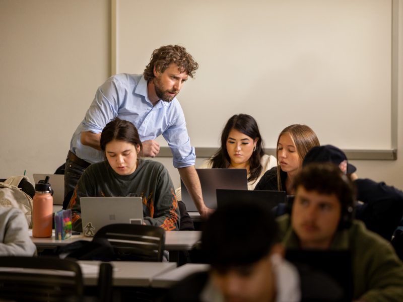 A professor collaborating with his students in a classroom.