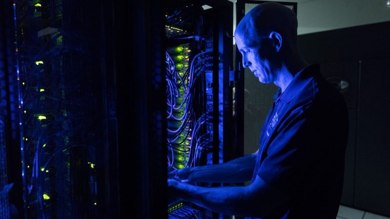 Chris Coffey adjusting cables on computer hardware.