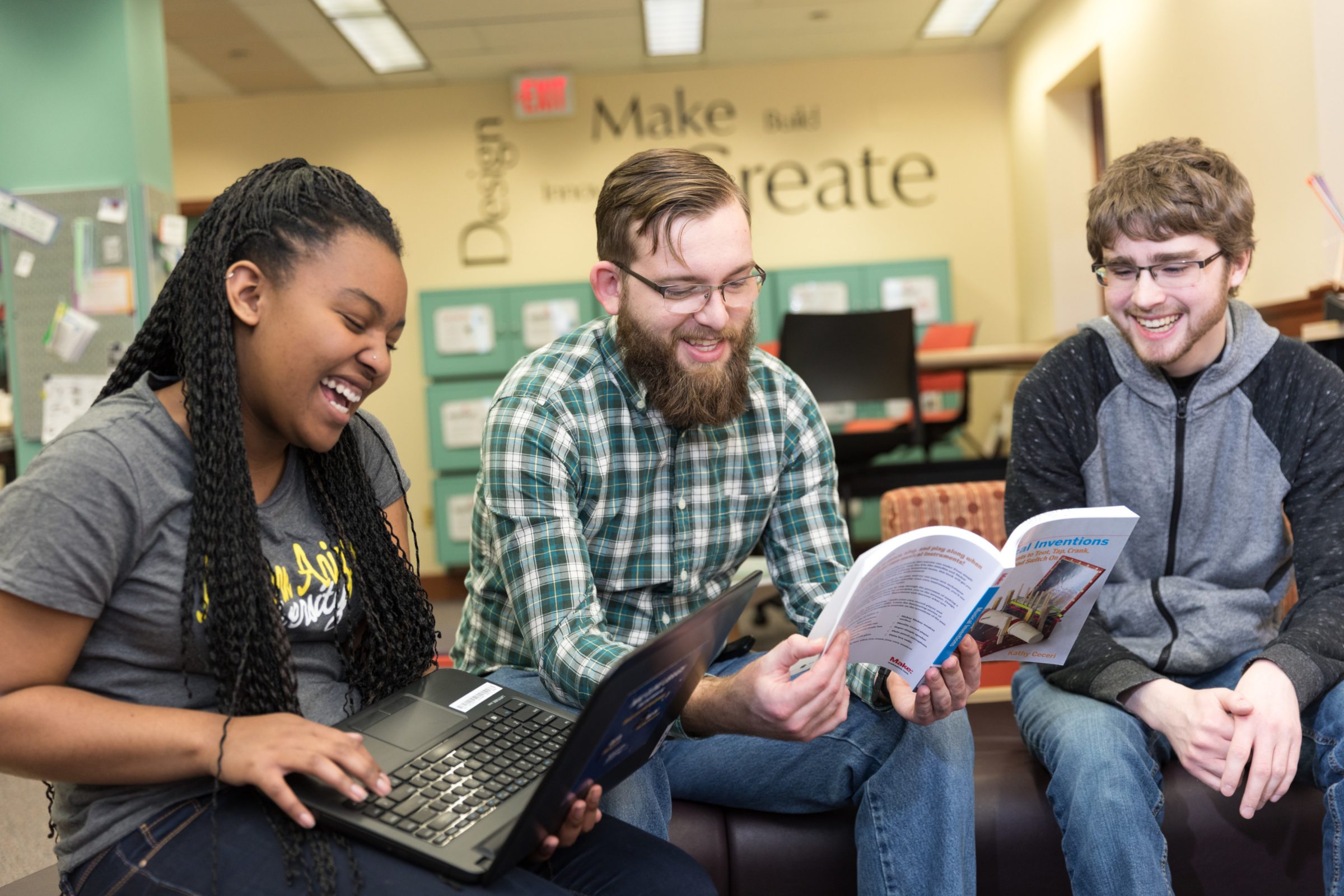 Three students looking at a book at the Cline Library.