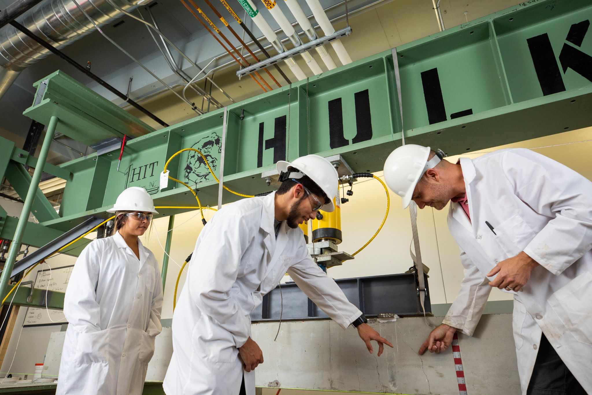 Engineering students making adjustments on industrial machines.